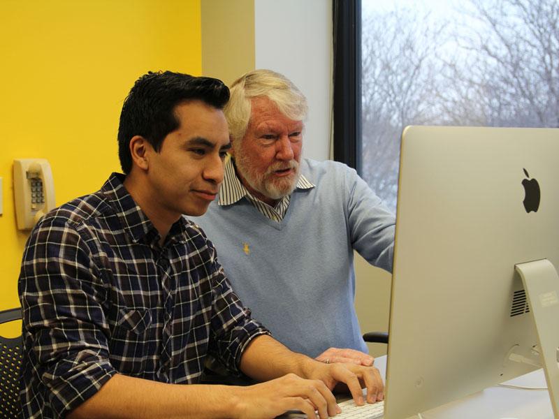 Student and professor working on a computer.
