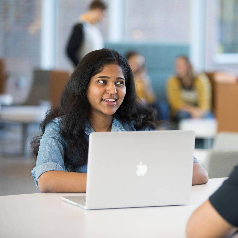 Female student smiling while working on laptop